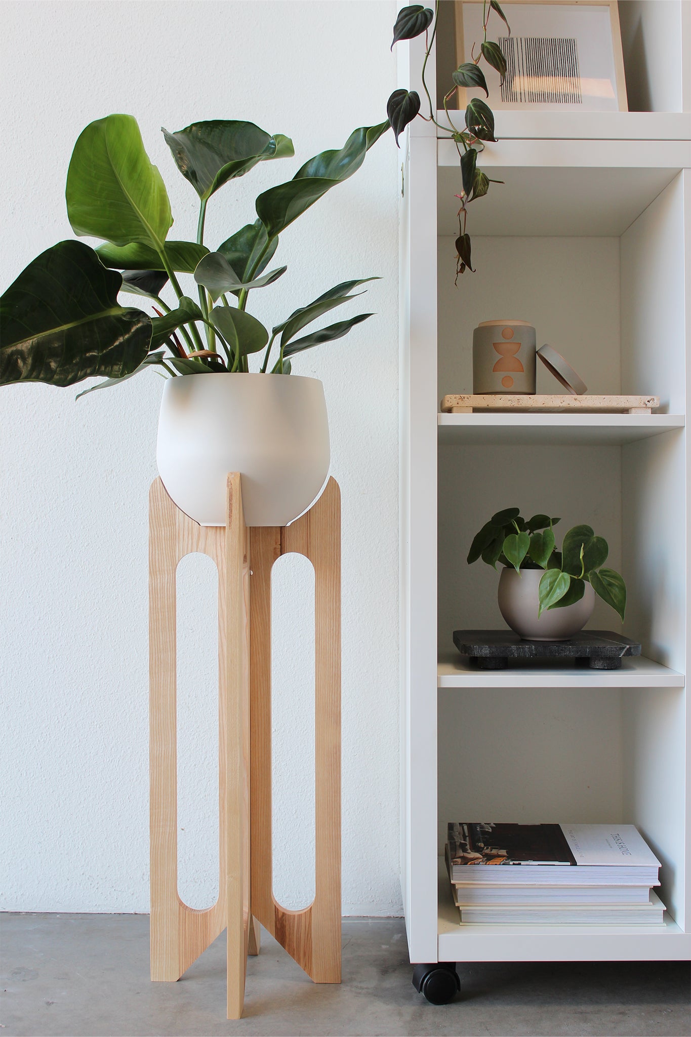 tall modern wood arches plant stand by Kandis Cottage styled against white bookcase and white accent wall