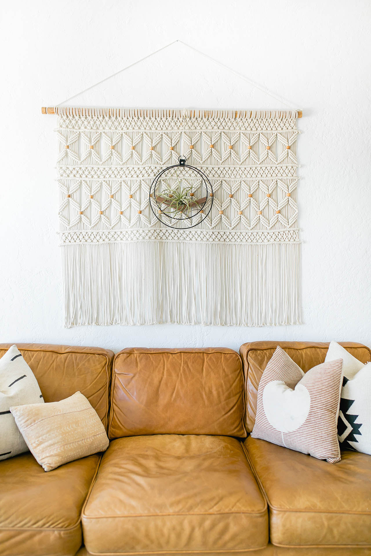 wall mounted air plant holder by Kandis Cottage styled on macrame tapestry above tan leather couch