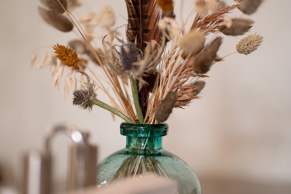 Pretty dried floral arrangement in aqua colored vase