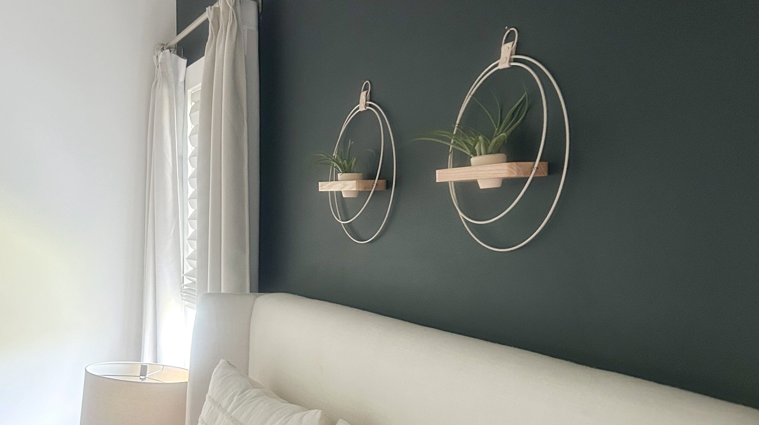 two modern plant shelves with white metal rings and blush terracotta pots against a dark bedroom wall