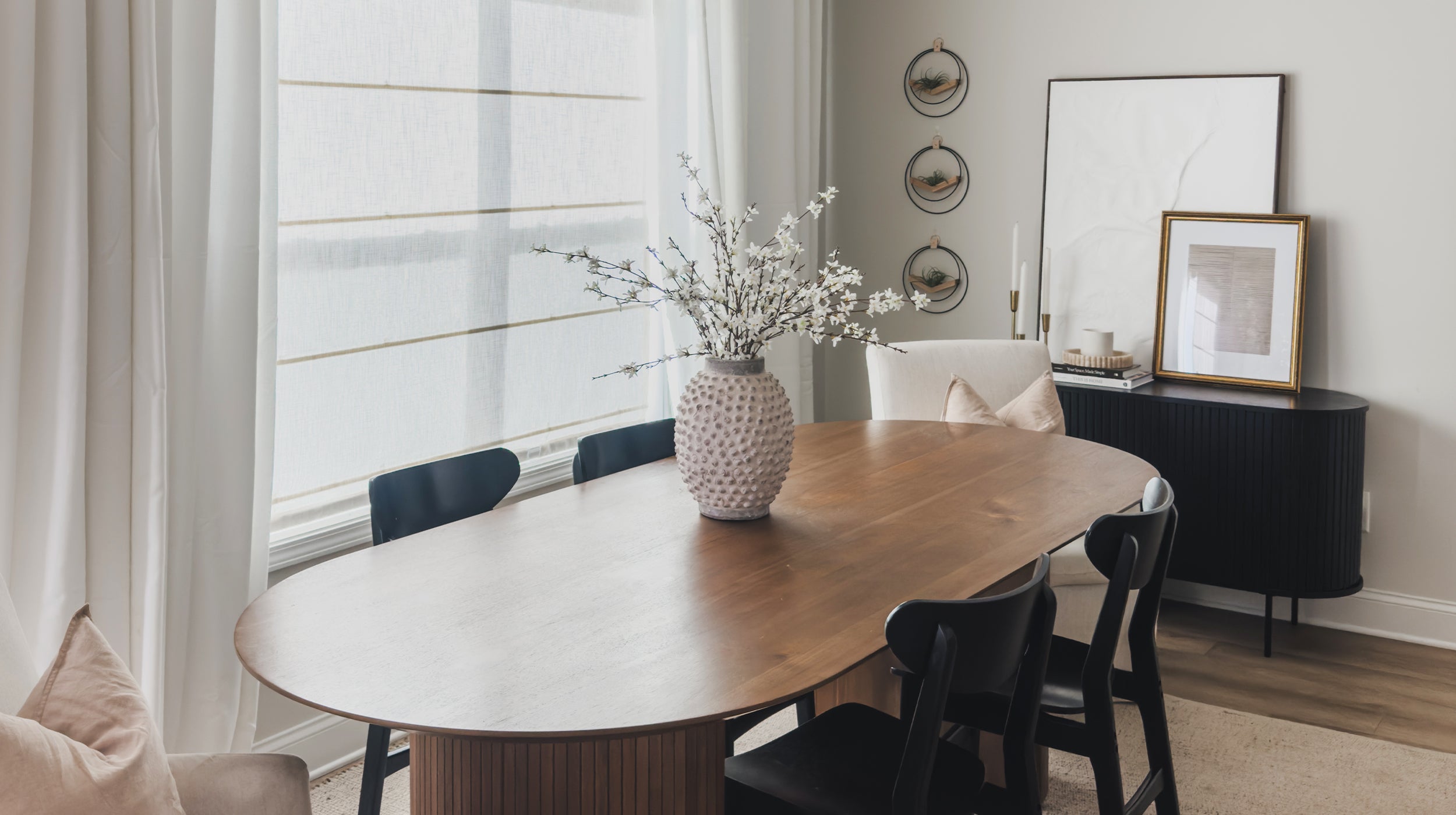 three modern air plant holders with black rings in a dining room next to framed art work