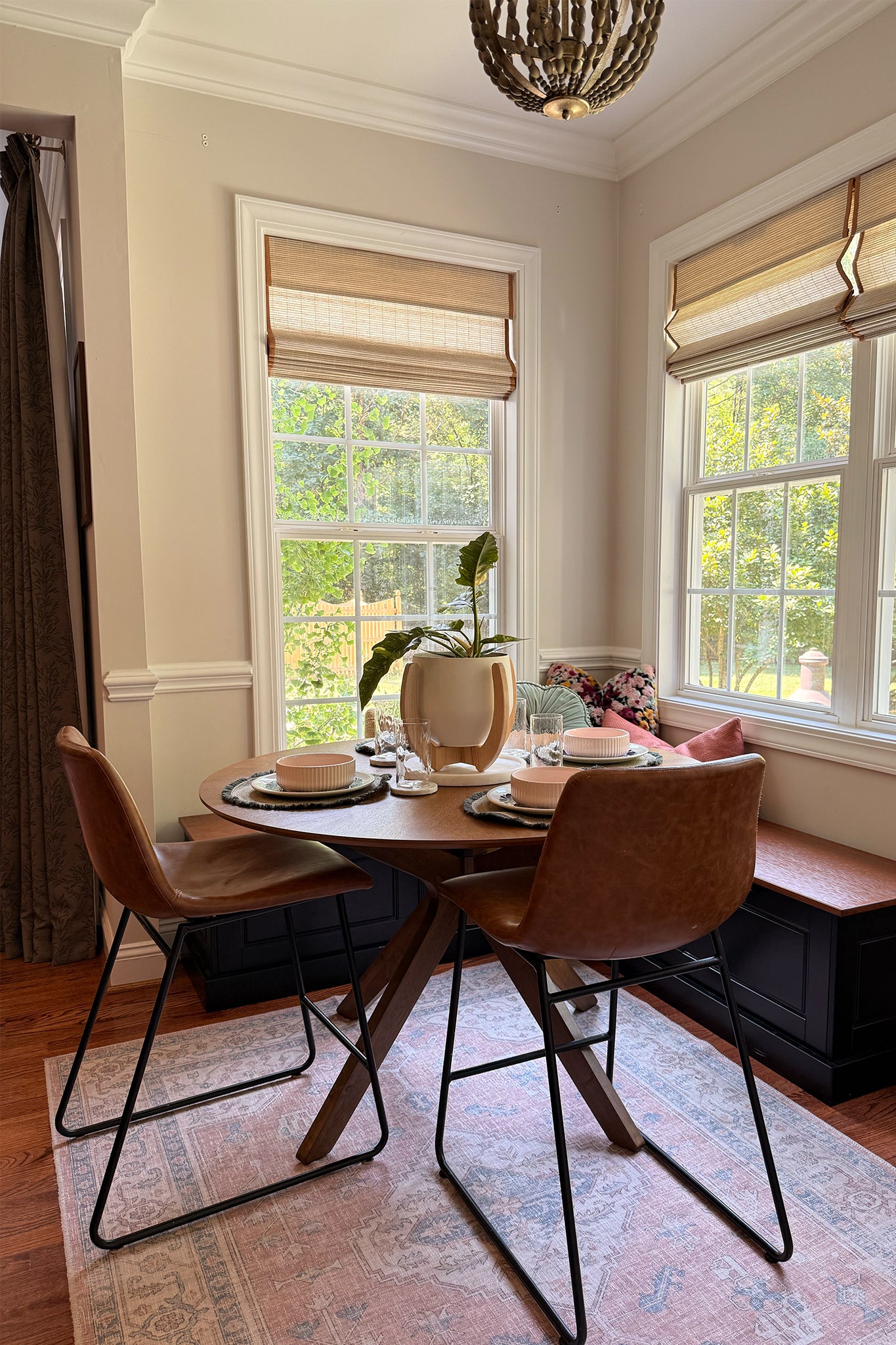Dining room with a round wooden table and brown chairs, large windows, and the Nested Plant Stand as a centerpiece.