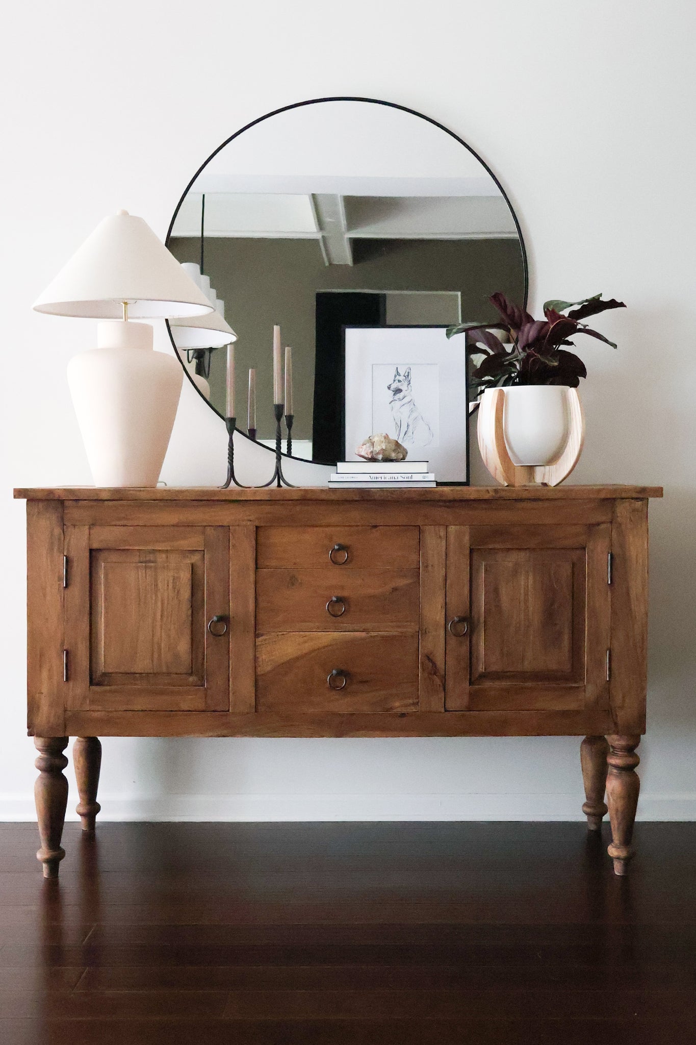 Wooden sideboard with round mirror, candles, and the Nested Plant Stand against a white wall.