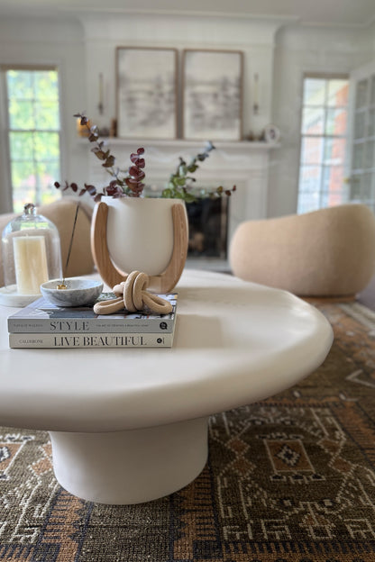 The Nested Plant Stand on a white, modern coffee table with other decorative elements like coffeetable books and incense. 