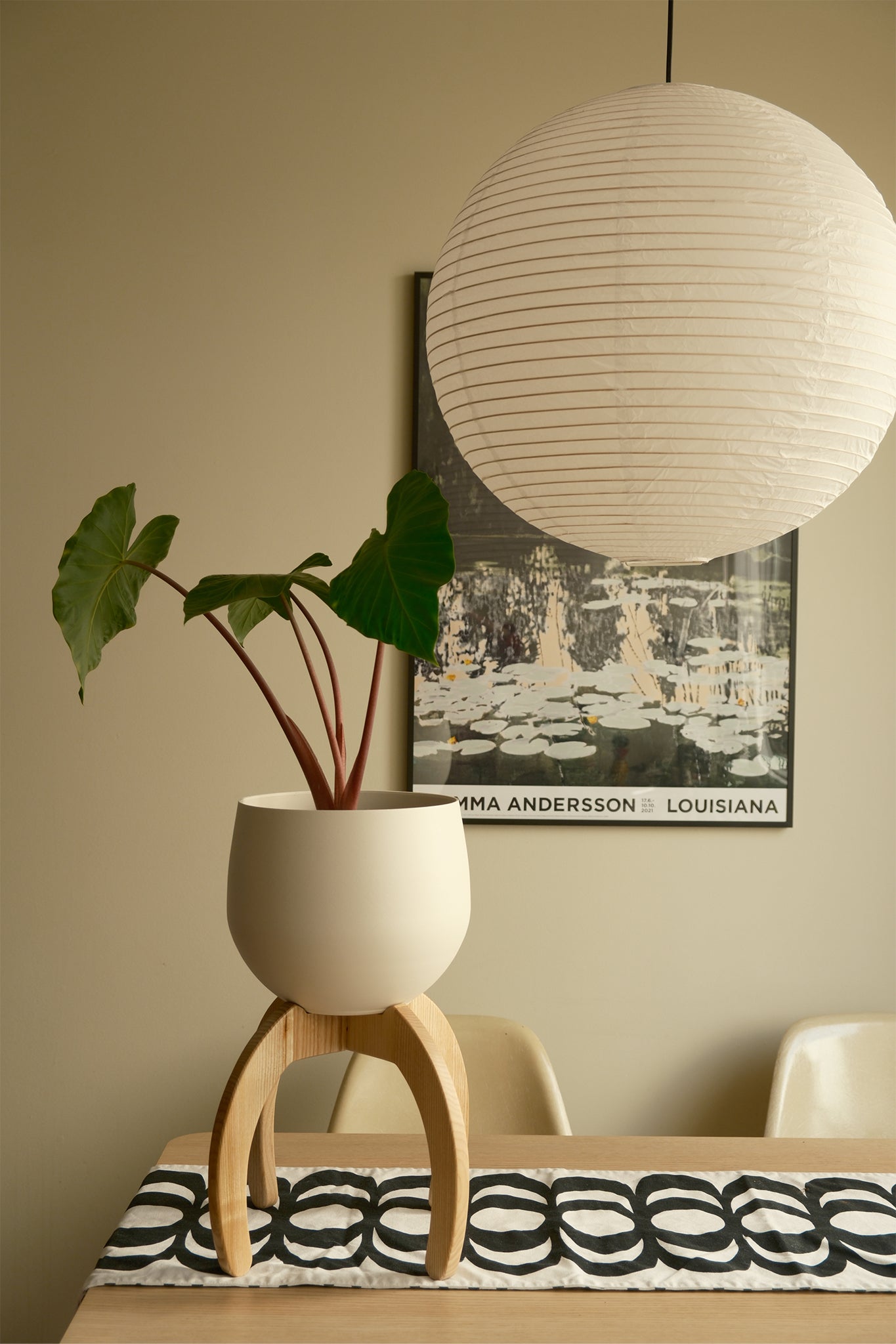 White lampshade hanging above a table with a Nested Plant Stand on the table.