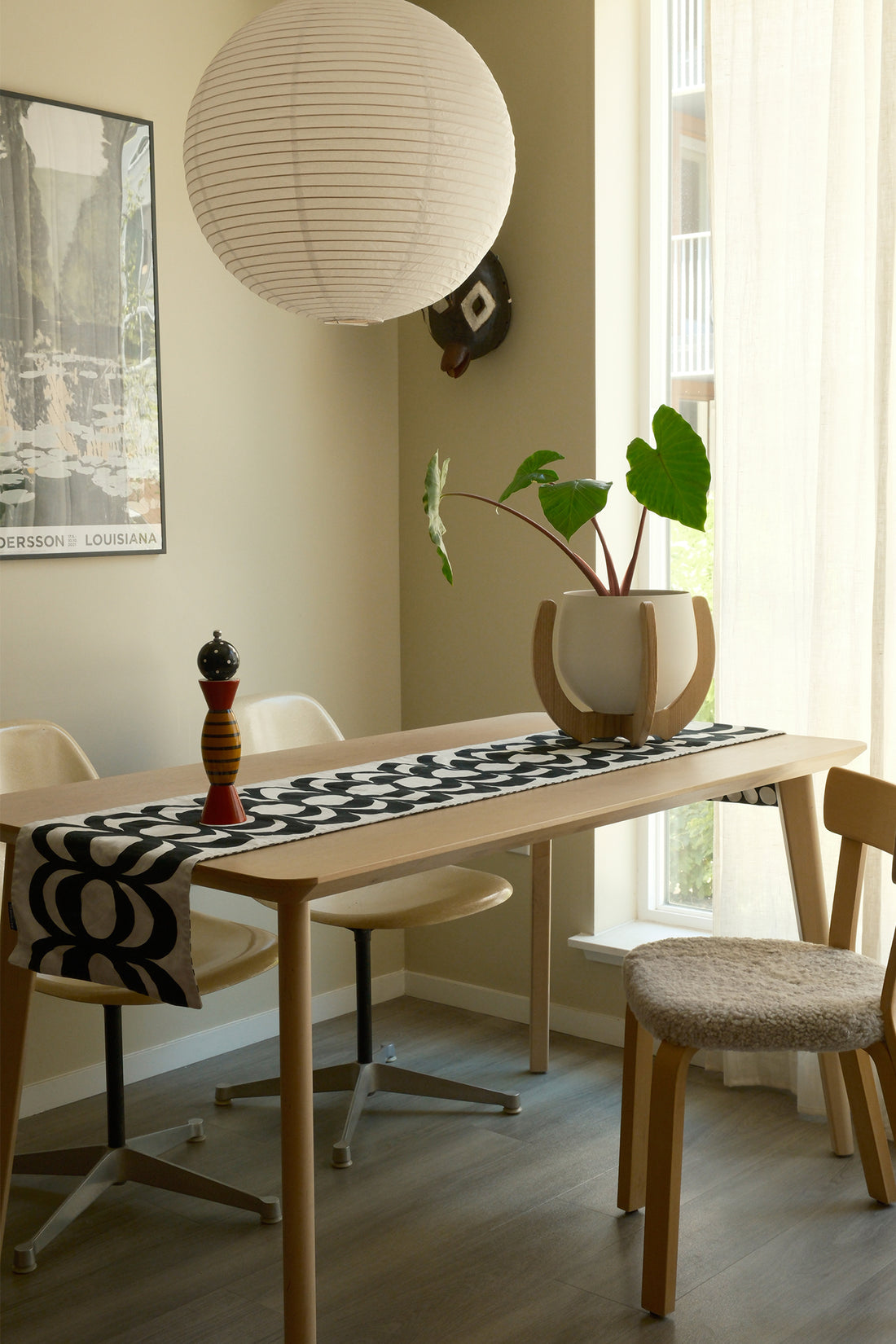 A modern dining room with a table, chairs, a paper lamp, and a Nested Plant Stand on the table.