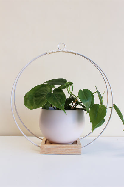large white circular plant hanger with blush colored aluminum pot for houseplants